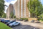 Suitland apartment for rent - A parking lot with cars and a tall building in the background at Ashton Heights Apartments, Suitland, MD