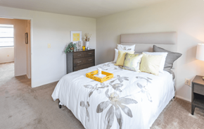 Baltimore apartment for rent - A bedroom with a large bed and a nightstand with a lamp at Dutch Village Apartments, Baltimore