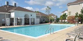 Suitland apartment for rent - a swimming pool with chairs around it in front of a building at Windsor Crossing, Suitland, MD 