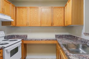 Suitland apartment for rent - A kitchen with wooden cabinets and a white stove top oven.