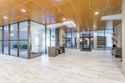 Greenbelt apartment for rent - A spacious hallway with a tiled floor and glass walls leading to an outdoor area at Charlestowne North Apartments, Greenbelt, MD