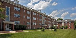 Silver Spring apartment for rent - A large red brick building with a green lawn in front. at University Landing Apartments, Silver Spring, MD