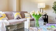 Suitland apartment for rent - A living room with a grey couch, a glass table, and a vase of white flowers at Ashton Heights Apartments, Maryland, 20746