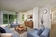 Greenbelt apartment for rent - A living room with a blue sofa, a wooden coffee table, and a large window with a view of trees at Charlestowne North Apartments, Maryland, 20770