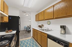 Frederick apartment for rent - kitchen at Creekside at Taskers Chance in Frederick, MD with black appliances, wood cabinets and white countertops