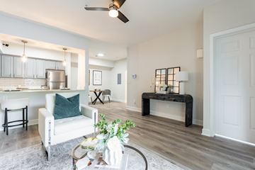 Goose Creek apartment for rent - A living room with a white chair and a table with a plant on it.