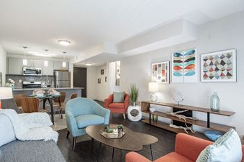 A living room with furniture and a kitchen in the background