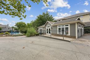 Prairie Village apartment for rent - A house with a grey roof and a grey garage door is surrounded by trees and a blue pool.