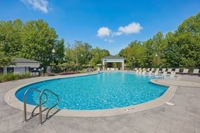 Knightdale apartment for rent - A large outdoor swimming pool surrounded by trees and a pavilion.