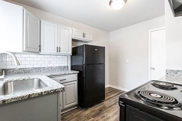 Atlanta apartment for rent - a kitchen with white cabinets and a black refrigerator