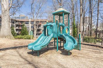 A playground with slides and a building in the background