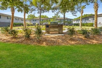 A garden with trees and a fountain in front of apartments