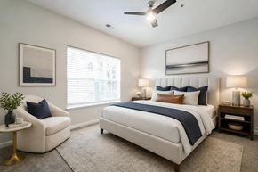 Moncks Corner apartment for rent - A bedroom with a large bed, a chair, and a ceiling fan.