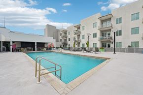 Sarasota apartment for rent - A swimming pool in front of a building with a metal railing.