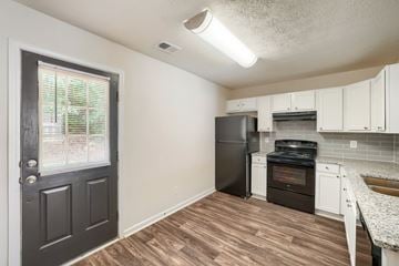 Commerce townhouse for rent - A kitchen with a black refrigerator and wooden floors.