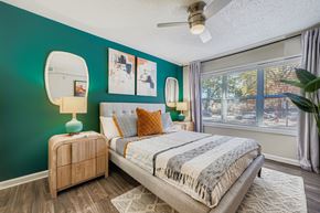 Atlanta apartment for rent - A bedroom with a bed, nightstand, and a window with a view of a building outside.