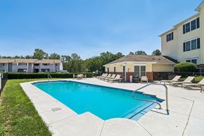 Fredericksburg apartment for rent - A swimming pool surrounded by lounge chairs and buildings.