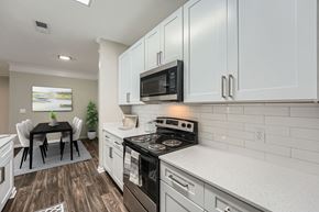 Kennesaw apartment for rent - A modern kitchen with white cabinets and a black stove top.