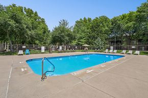 West Des Moines apartment for rent - A large blue swimming pool surrounded by trees and chairs.