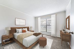 Prairie Village apartment for rent - A bedroom with a large bed, a nightstand, and a window with blinds.