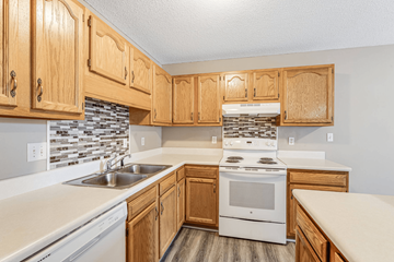 Asheville apartment for rent - A kitchen with wooden cabinets and a white stove top oven.