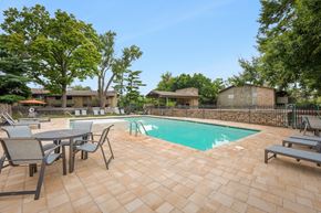 Prairie Village apartment for rent - A patio with a table and chairs is surrounded by a pool.
