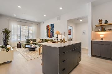 West Jordan apartment for rent - A modern kitchen with a large island and a living room with a sofa and a coffee table.
