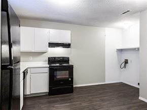 Fayetteville apartment for rent - an empty kitchen with white cabinets and a black stove and refrigerator