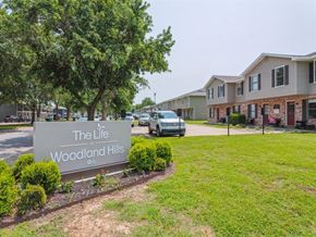Springdale apartment for rent - A sign for The Life Woodland Hills is in front of a row of houses.