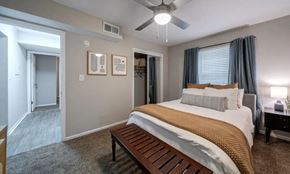 Smyrna apartment for rent - A bedroom with a bed, a bench, and a ceiling fan.
