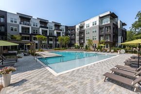 Charlotte apartment for rent - a swimming pool with lounge chairs and umbrellas in front of an apartment building at Century University City, Charlotte, 28213