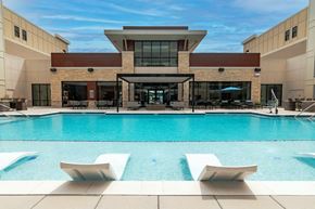 Lee's Summit apartment for rent - a swimming pool with lounge chairs and umbrellas in front of a building  at Century West Pryor, Lee's Summit, MO