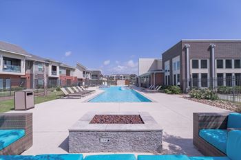 A swimming pool with a fire pit in front of an apartment building