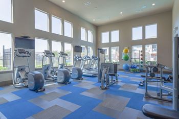 A gym with cardio equipment and windows in a building