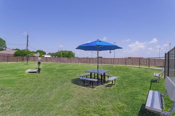 A patio with a picnic table and an umbrella in a backyard