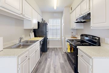 Burleson apartment for rent - A kitchen with black appliances and white cabinets.