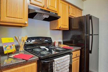Burleson apartment for rent - A kitchen with a black stove top oven and a black refrigerator.