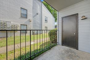Little Rock apartment for rent - A black metal fence separates a white house from a grey building.