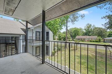 Little Rock apartment for rent - A balcony with a black railing overlooks a green lawn and a white house.
