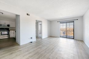 Kansas City apartment for rent - A spacious room with wooden flooring and a sliding glass door leading to a balcony.