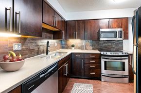 Kansas City apartment for rent - A kitchen with dark wood cabinets and a black fridge.
