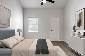 Prairie Village apartment for rent - A bedroom with a bed, a window with blinds, a ceiling fan, and a nightstand with a plant on it.