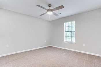 An empty room with a ceiling fan and a window