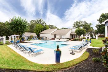 A swimming pool with lounge chairs around it in front of a house