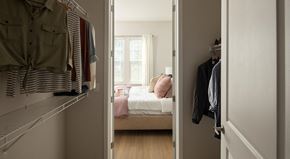 Clearwater apartment for rent - A bedroom with a bed and a closet with clothes hanging.