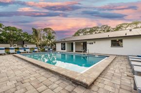 Largo apartment for rent - A swimming pool surrounded by a brick patio and a white building.
