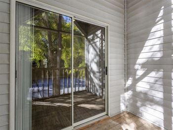 A sliding glass door with a reflection of trees and a pool.