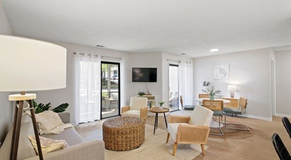 Columbus apartment for rent - A living room with a grey sofa, a wicker ottoman, a wooden coffee table, and a TV mounted on the wall.