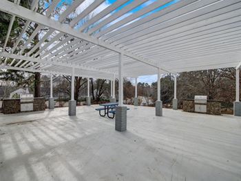 A covered patio with a table and a bench under a white roof