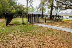 Georgetown apartment for rent - A black metal fence with a gate is in front of a grassy area with fallen leaves.